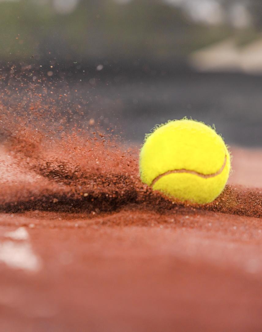 Tennisball wirbelt ordentlich roten Sand auf Tennisplatz auf